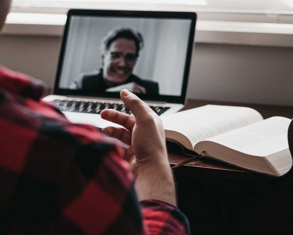 Man works remotely and talks to his colleague on Zoom. 